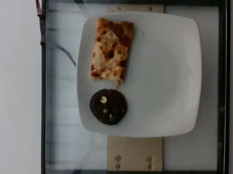 A slice of cheese pizza and a chocolate cookie on a white plate.